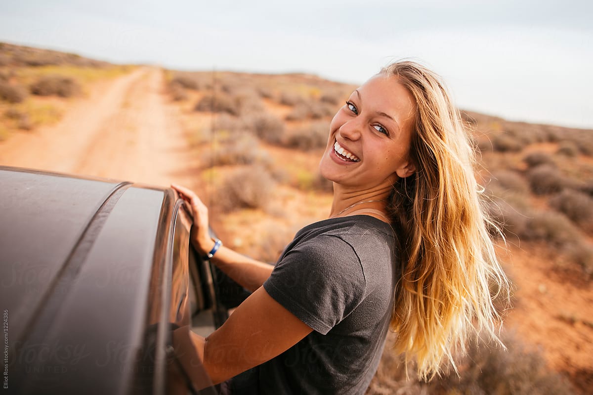 Young female smiles while hanging out of a truck window