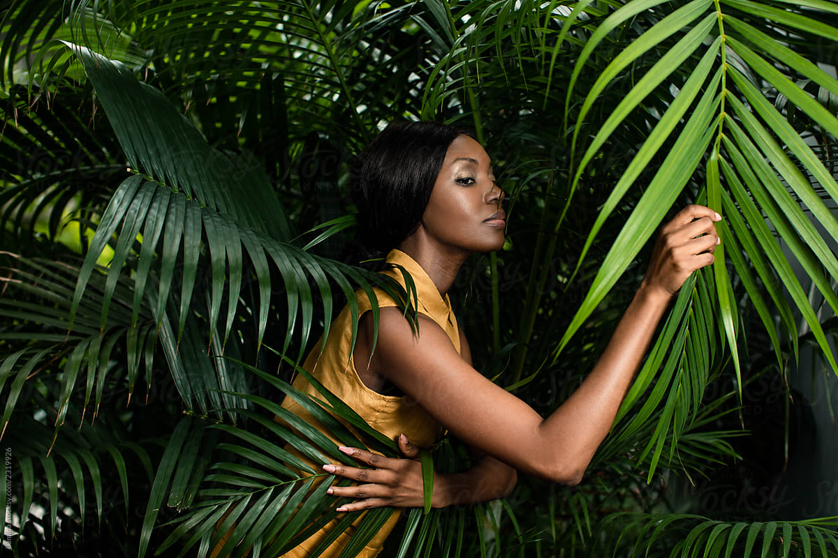 Fashion Portrait of a Woman Standing by the Palm Leaves