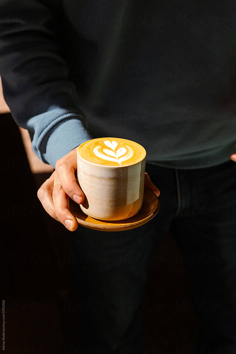 Barista holds a cup of specialty flat white coffee