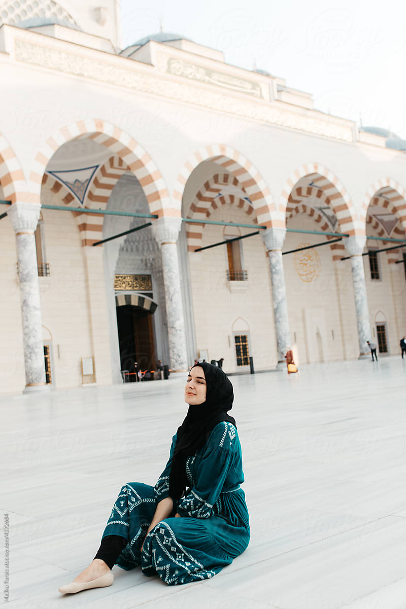 hijabi woman sitting in a mosque yard.