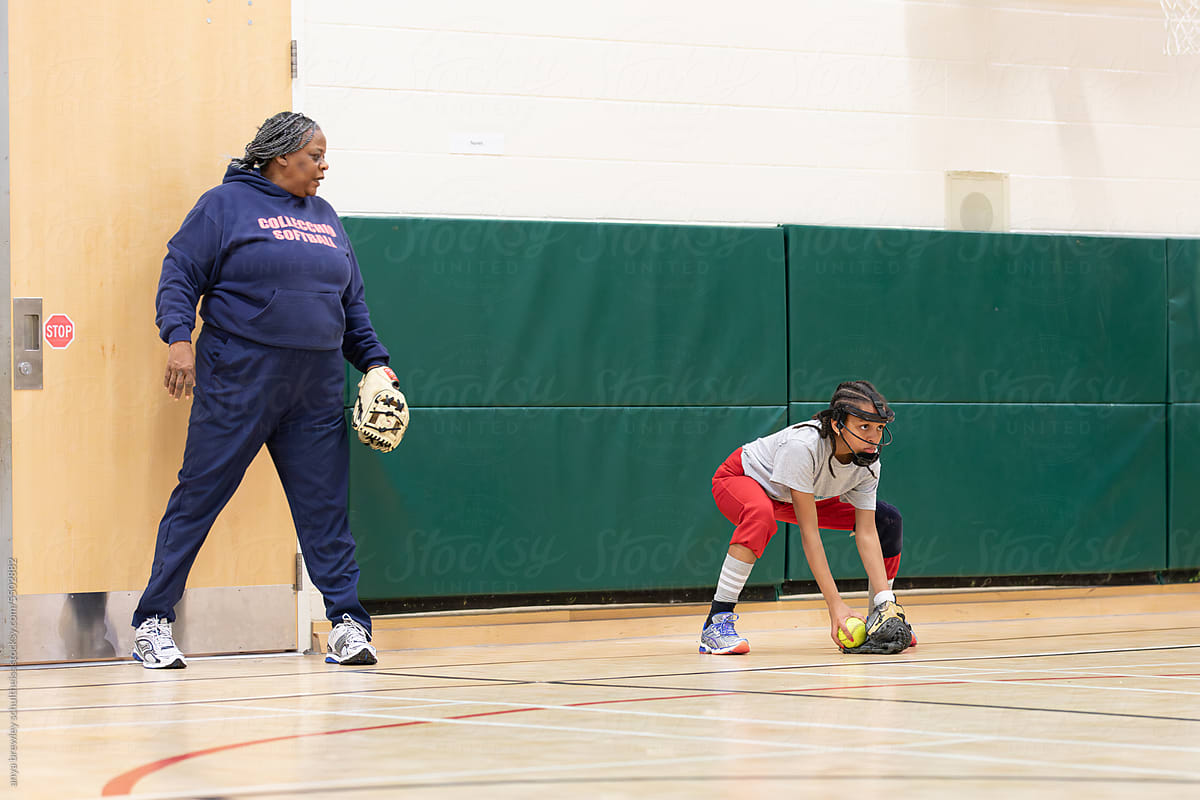 Woman training a child in fielding grounders for softball