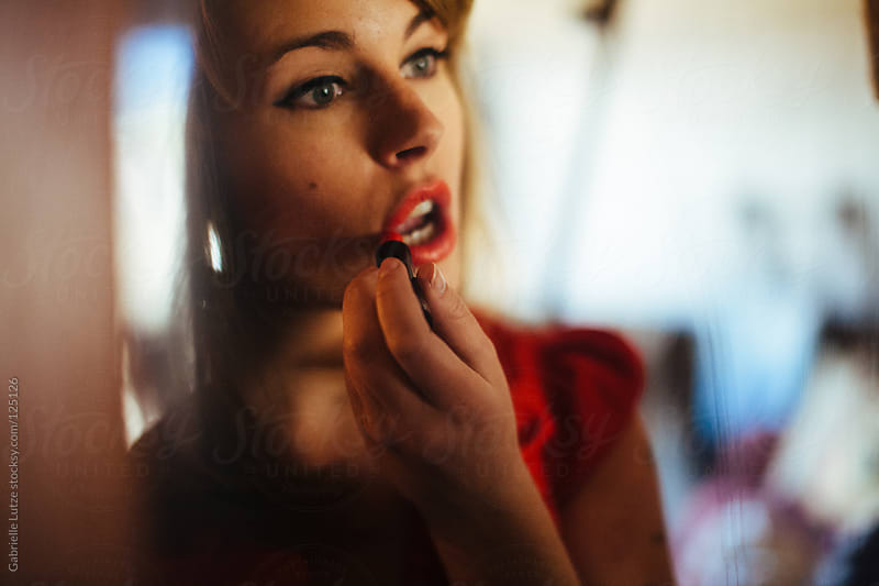 Woman Putting On Lipstick In The Mirror By Gabrielle Lutze Stocksy United