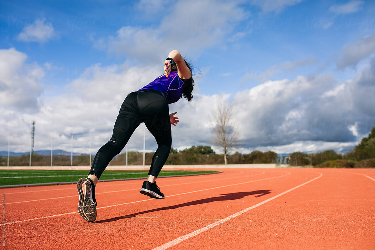 Unrecognizable sportswoman running on track