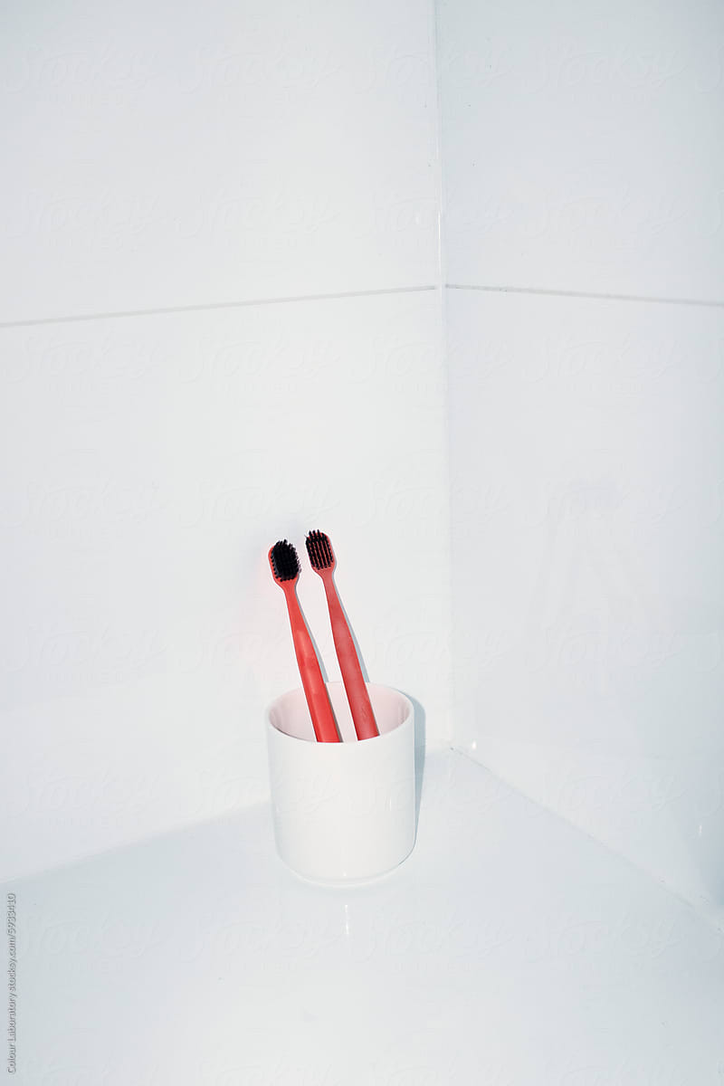 Couple of red toothbrushes on toilet with hard direct flashlight