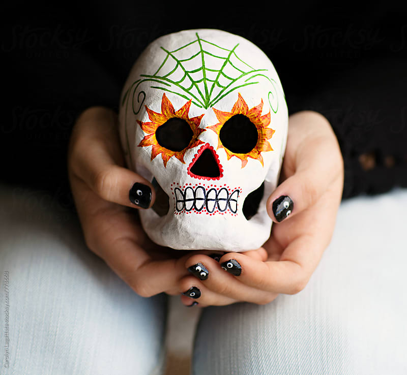 Girl holding a painted paper mache\' sugar skull with black nails for Halloween