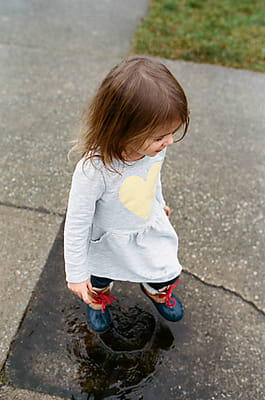 Little Girl Jumps In Puddle by Stocksy Contributor Maria Manco