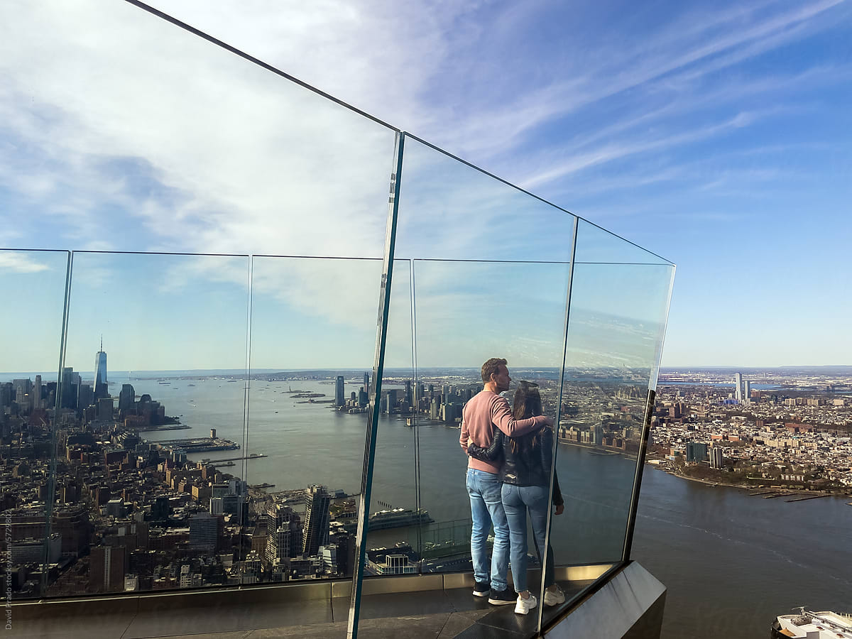 Man and Woman Overlooking Manhattan from Transparent Balcony