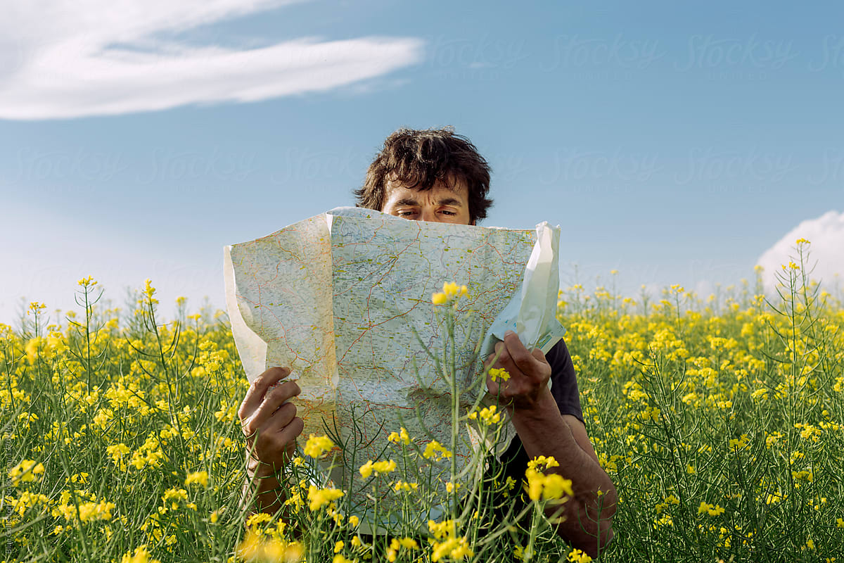 Man reading a map lost among flowers field