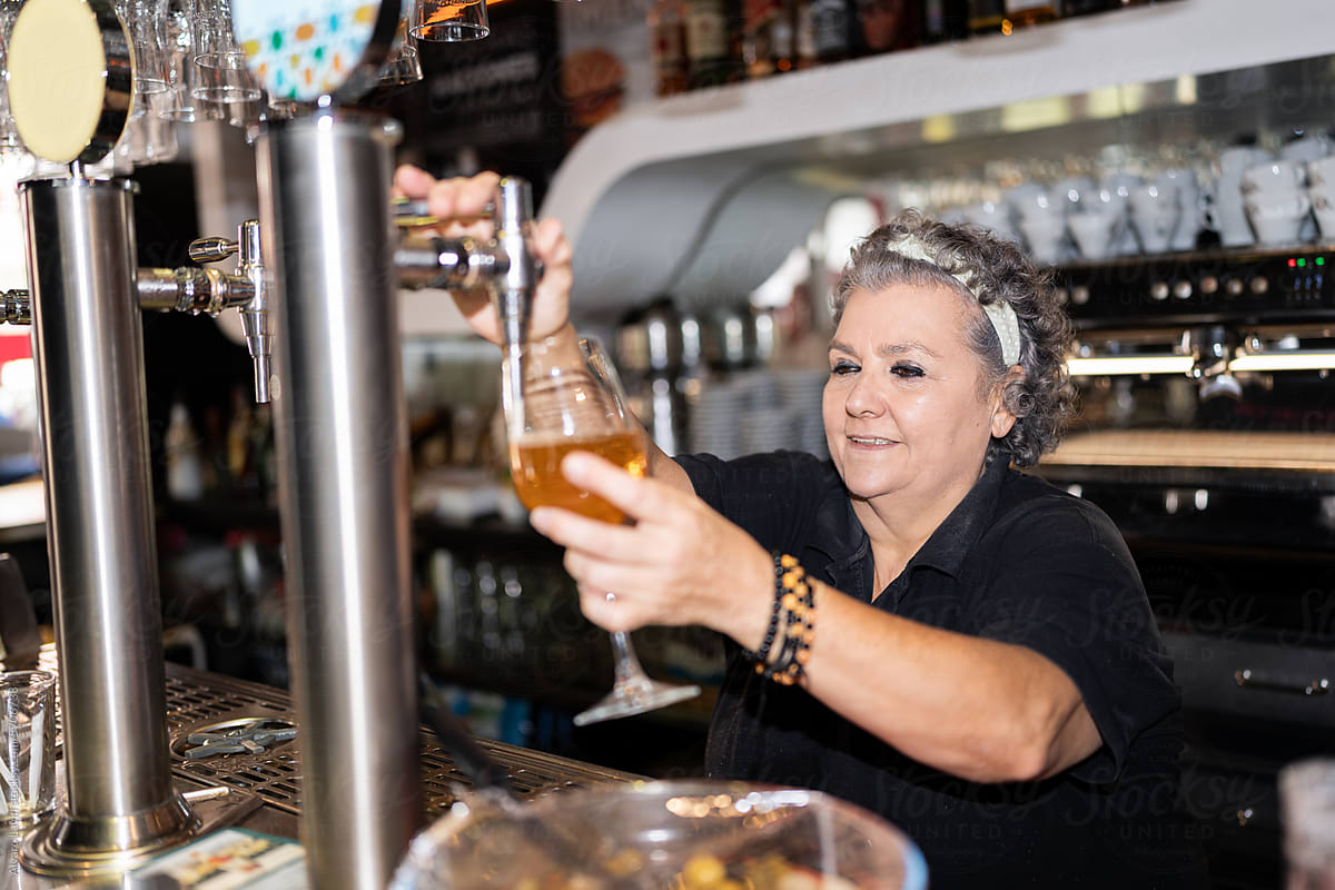 Senior waitress serving beer.