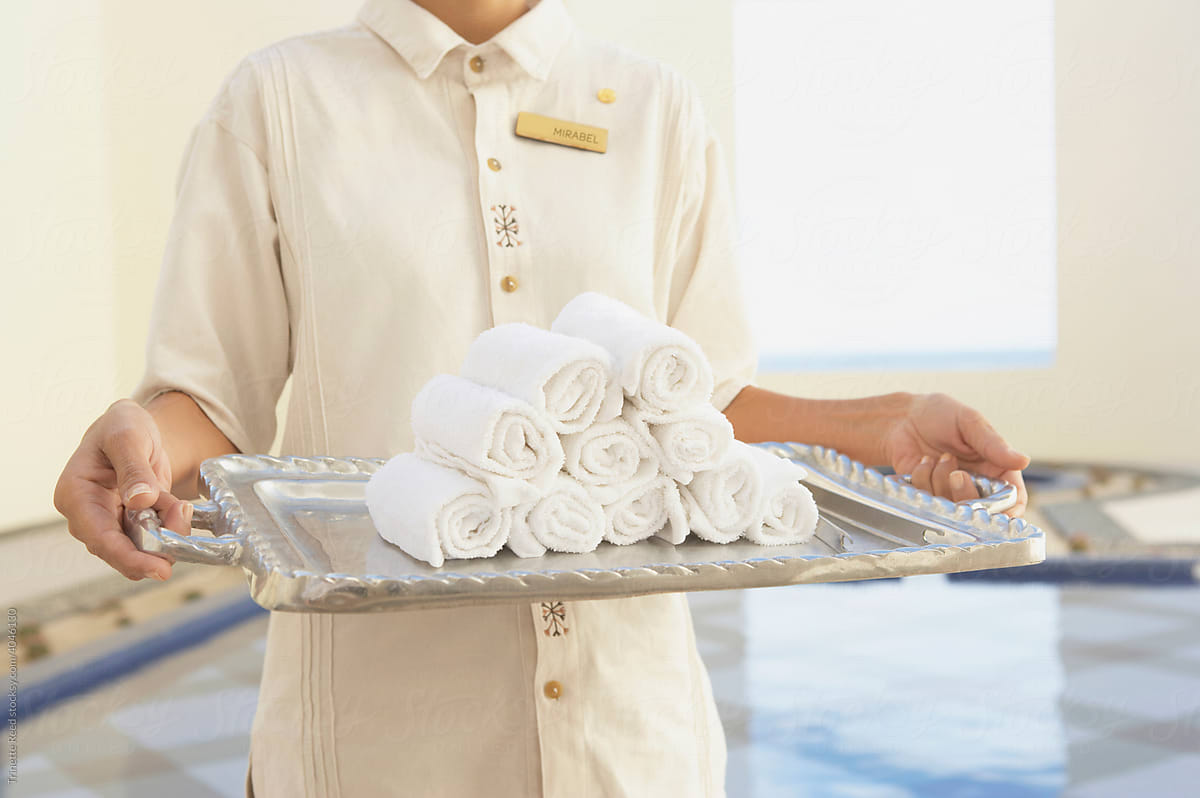 Hotel service employee holding tray with towels