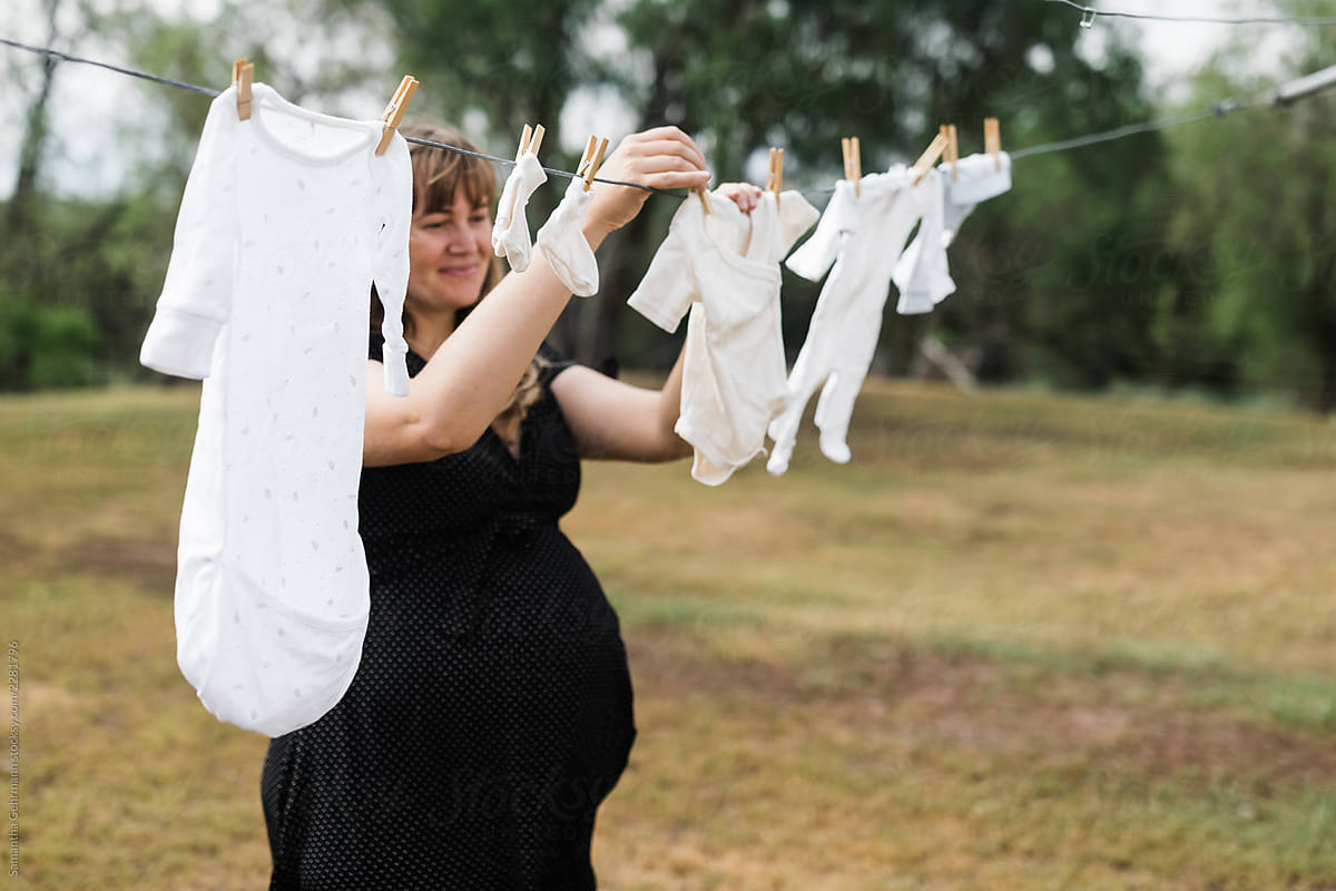 heavily pregnant woman hanging out laundry