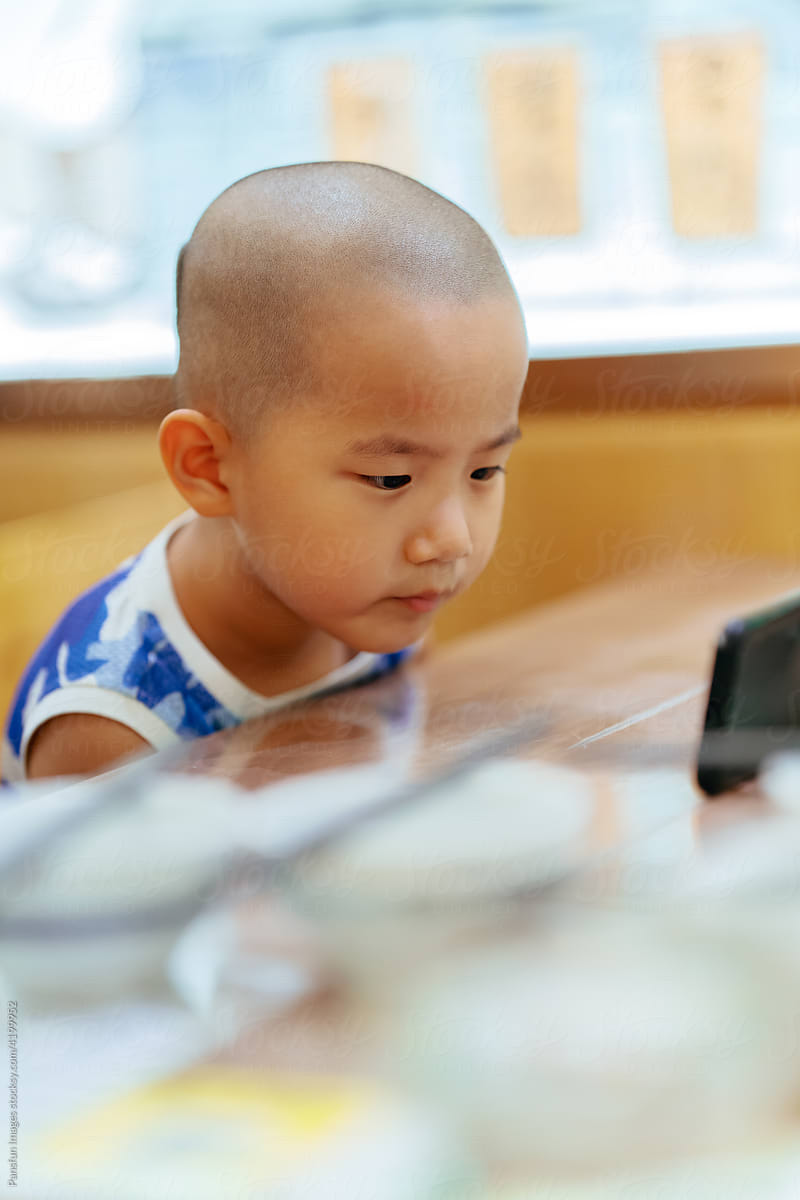 Asian little boy watching cell phone