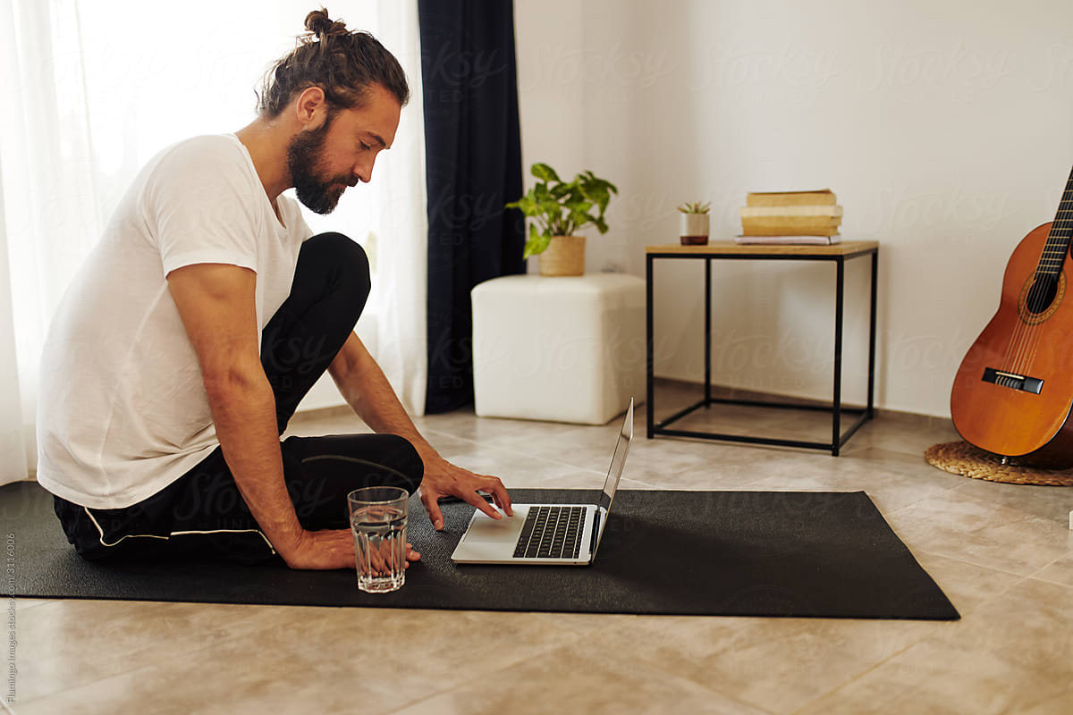 Man sitting on an mat at home using a laptop