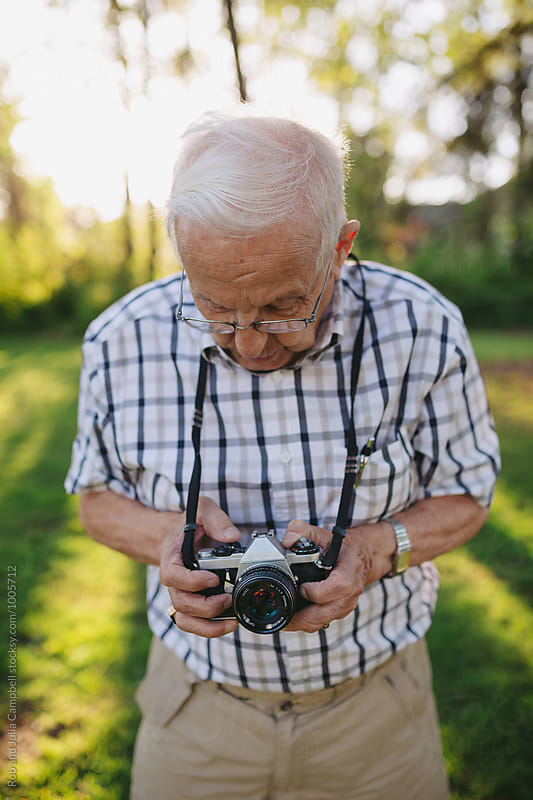 Old senior man taking pictures with old slr film camera