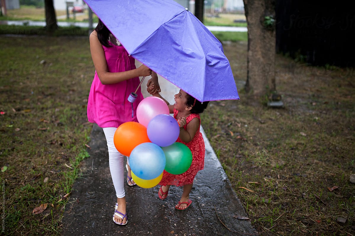 Sisters under umbrella and making fun with balloons