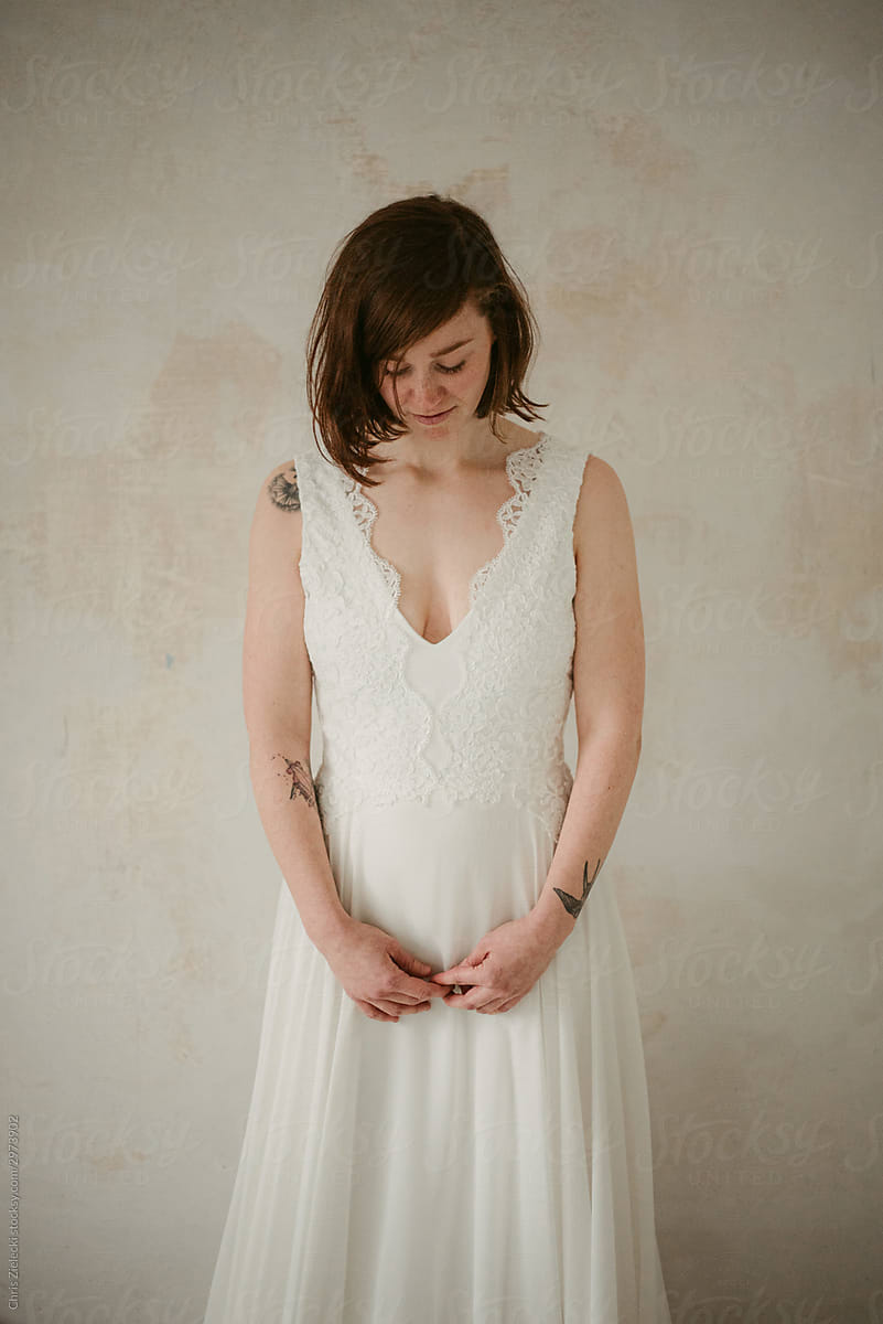 Tender young bride with tattoos in wedding gown