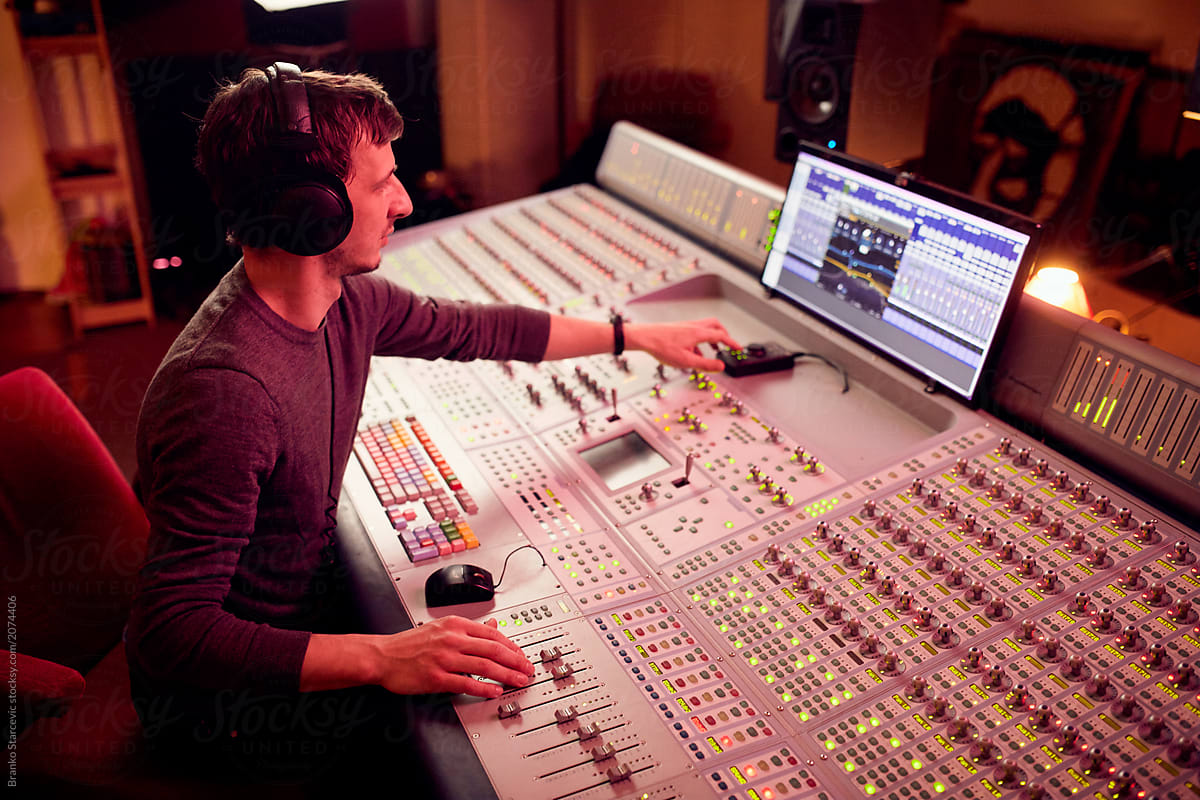 Sound Engineer mixing tracks in music studio.
