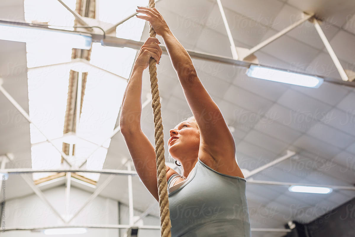 Strong woman climbing rope