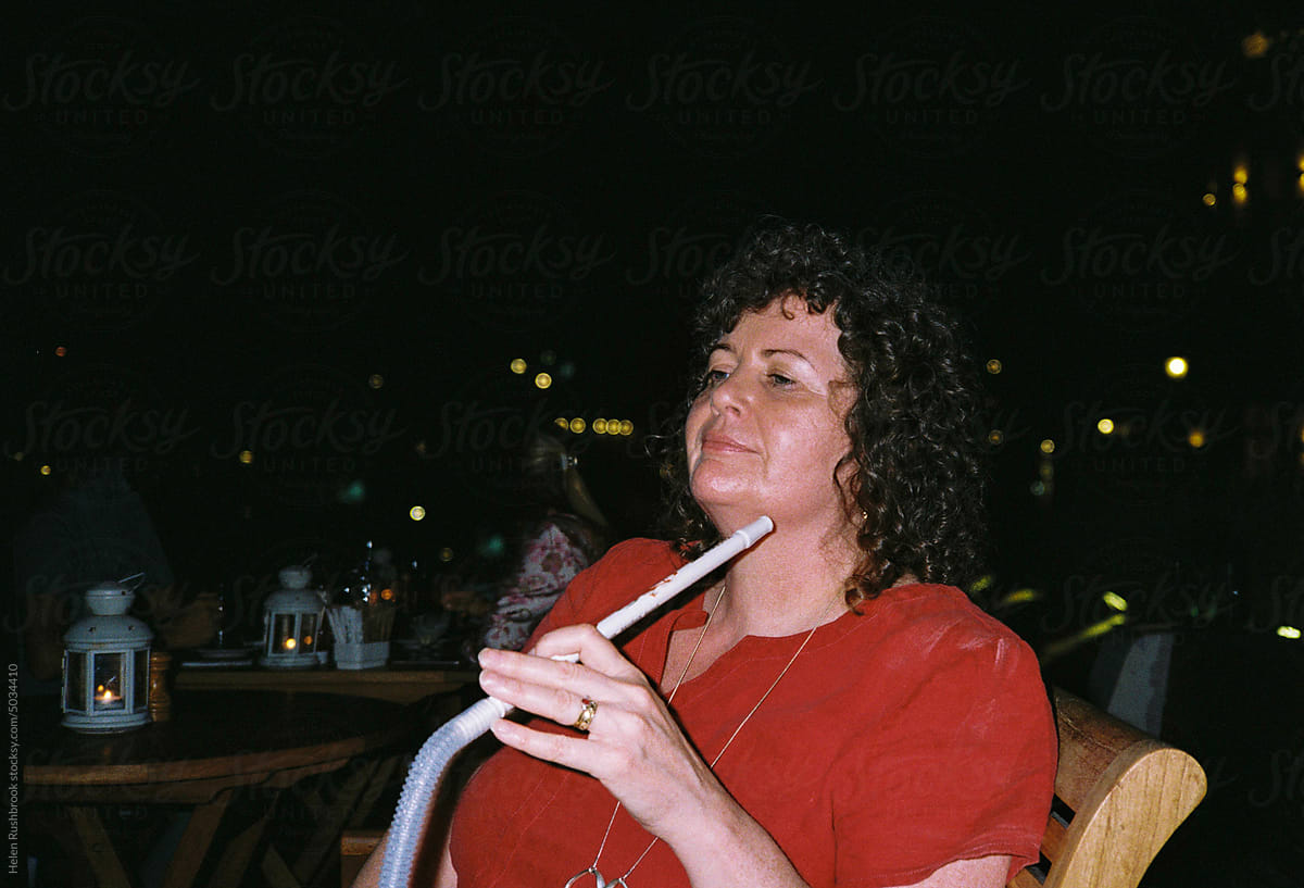 Woman looking relaxed at night with a shisha pipe.