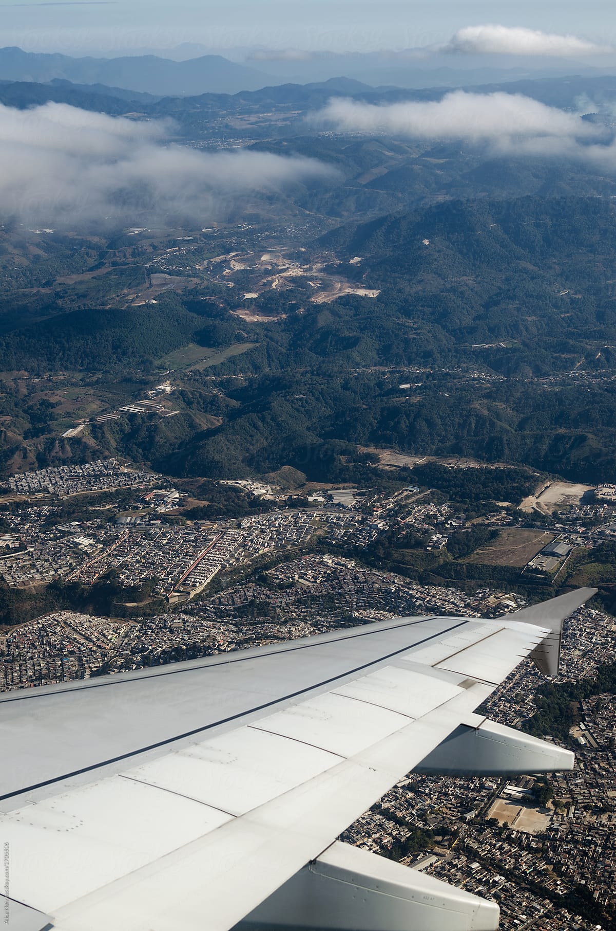 Airplane wing over Guatemala city and mountains