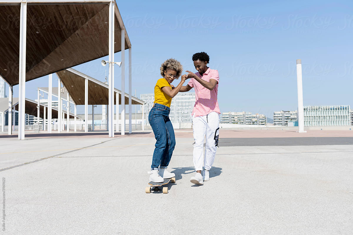 Boyfriend teaching girlfreind to skateboard.