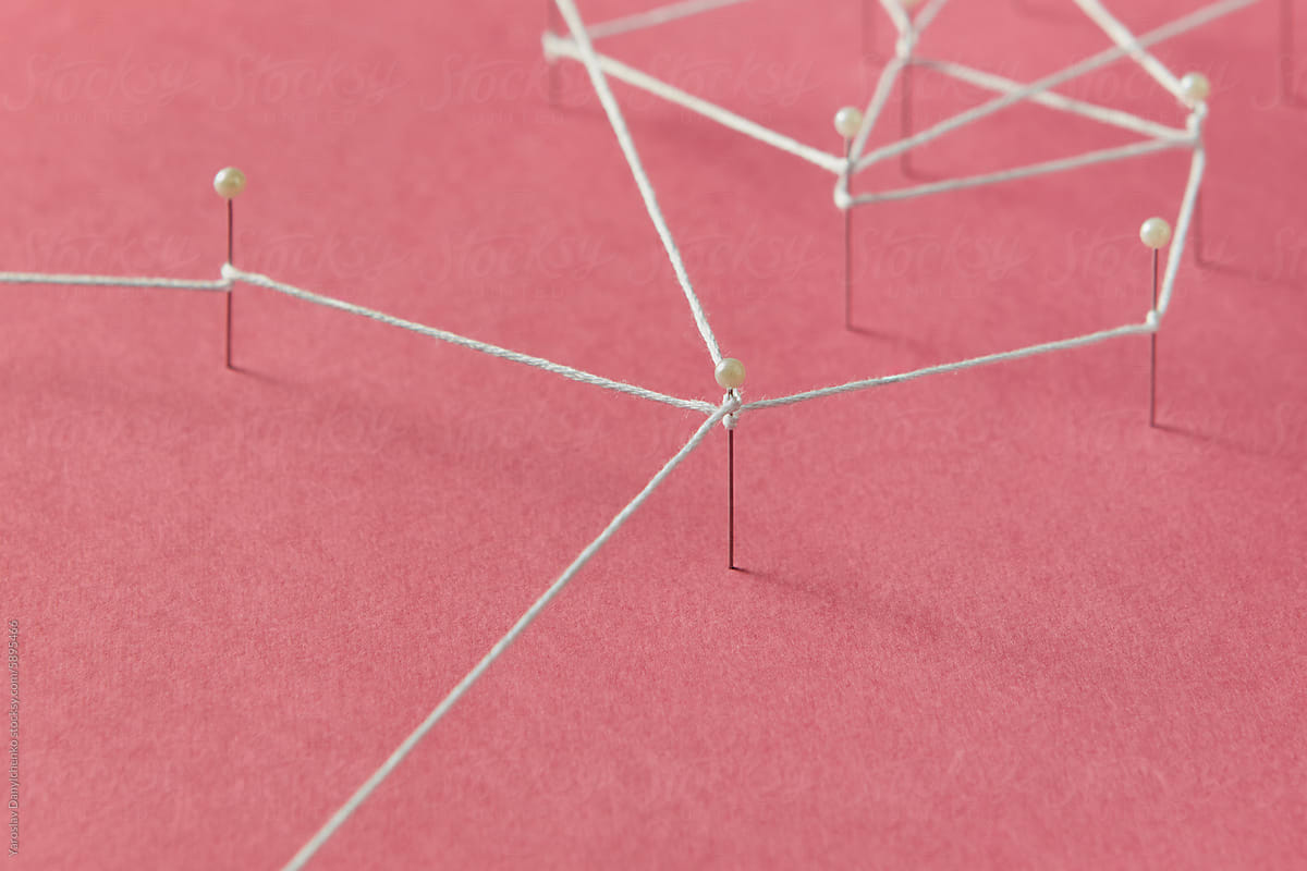 Stationery push pins connected with thread stuck on red paper