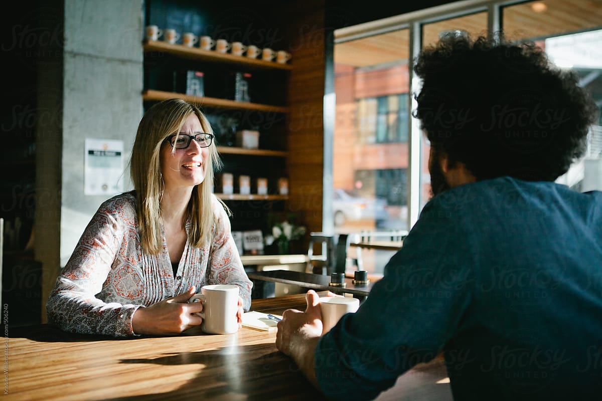 Woman smiling while chatting with a man over coffee