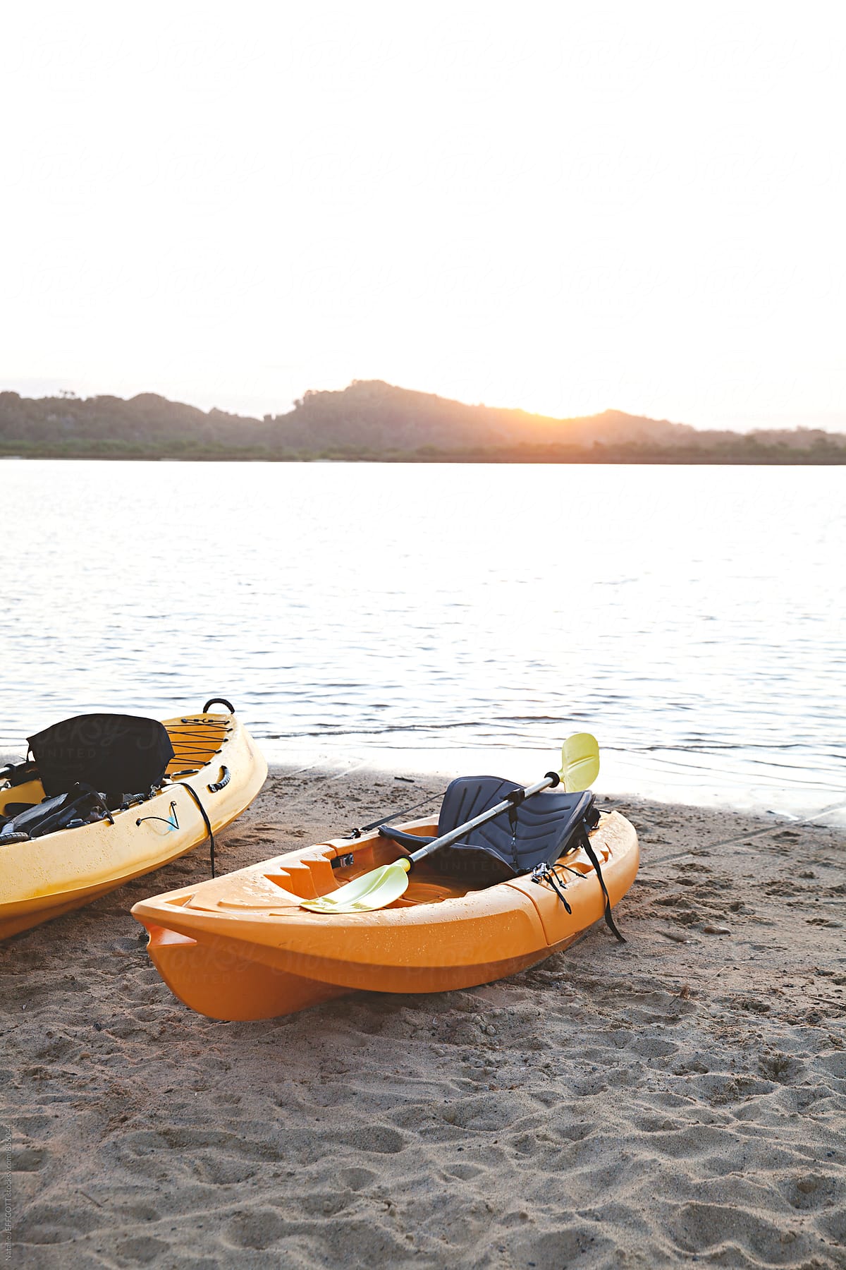 Yellow kayaks sit on a beach at sunset after a day paddling