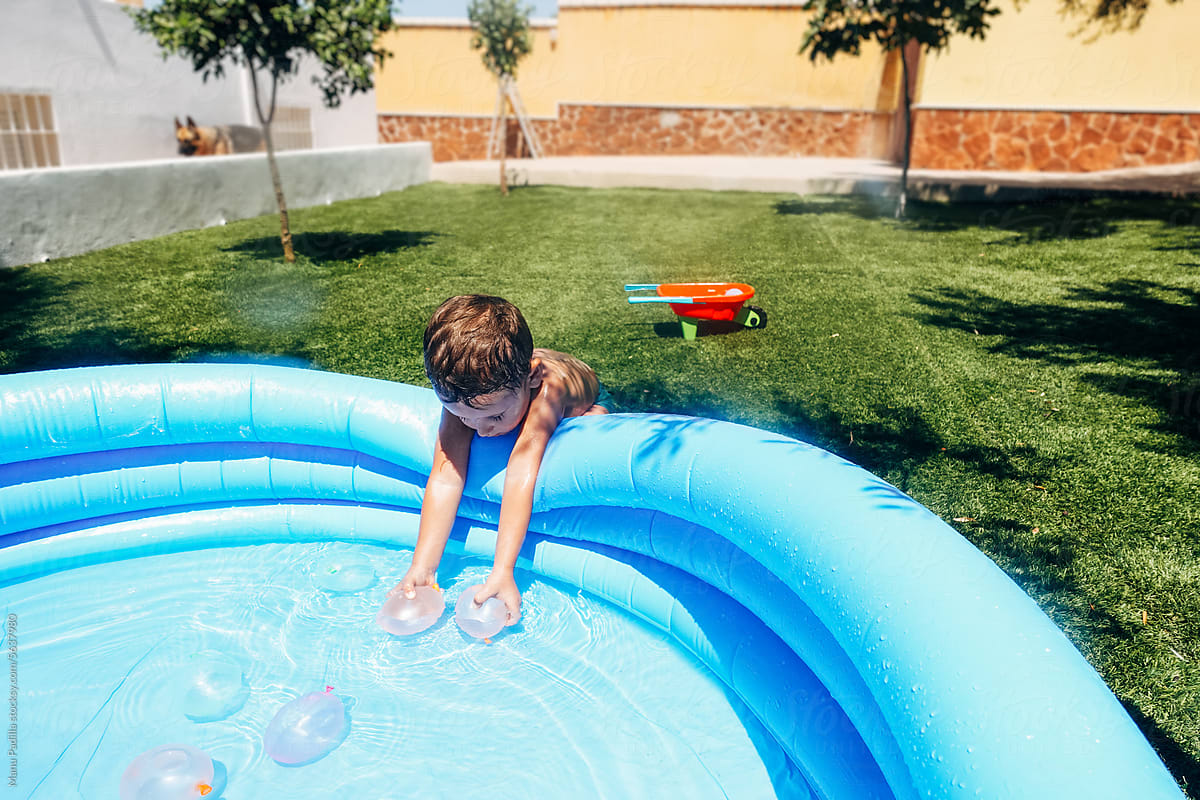 Boy placing water balloons in pool