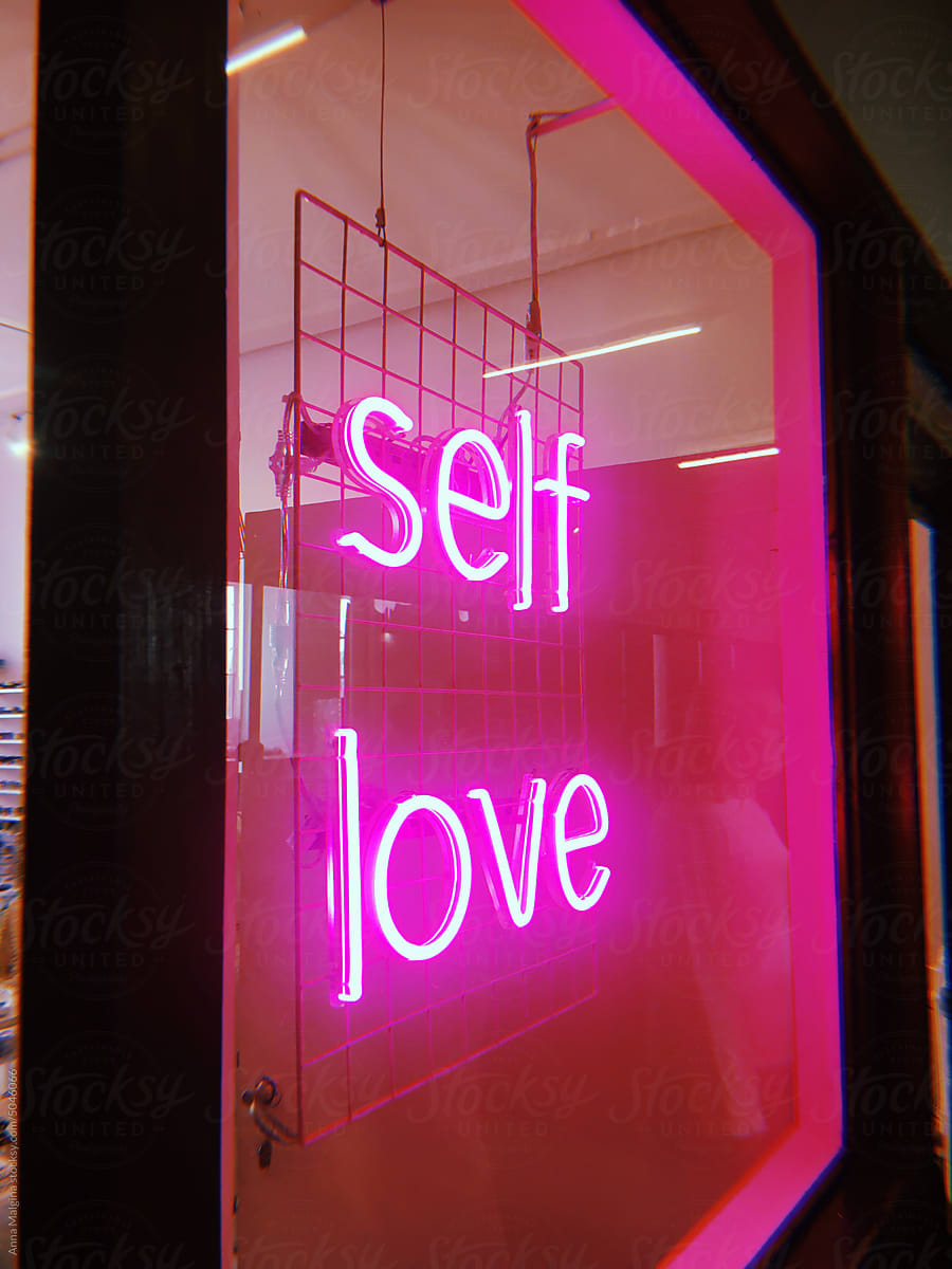 A pink neon sign self love at night
