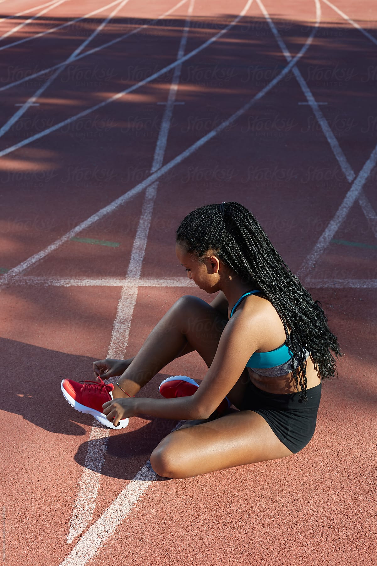 Black athlete tying her footwear in track and field