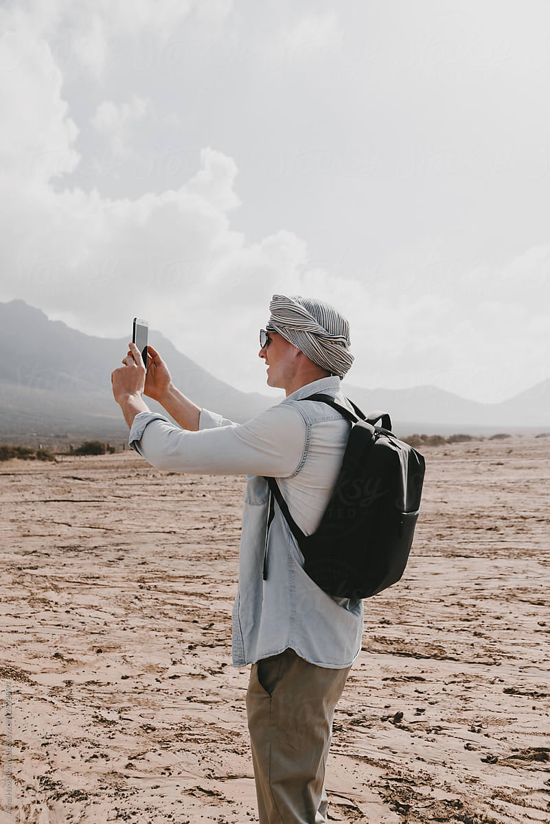 Stylish man taking photo on smartphone of mountains.