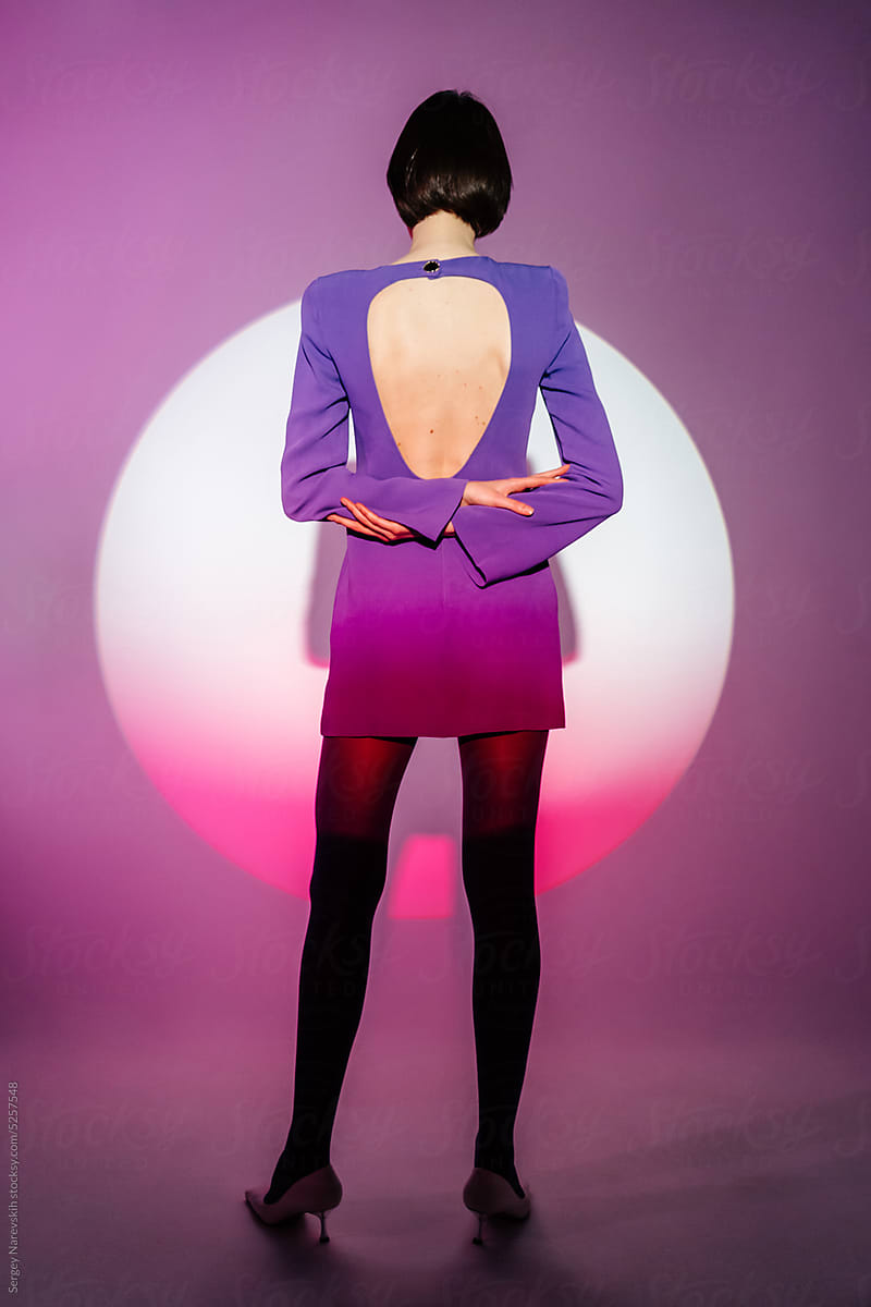 Back view of model in purple dress against round shaped illumination