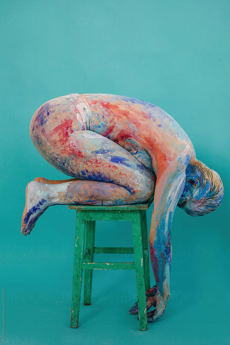 Model with body art kneeling on stool