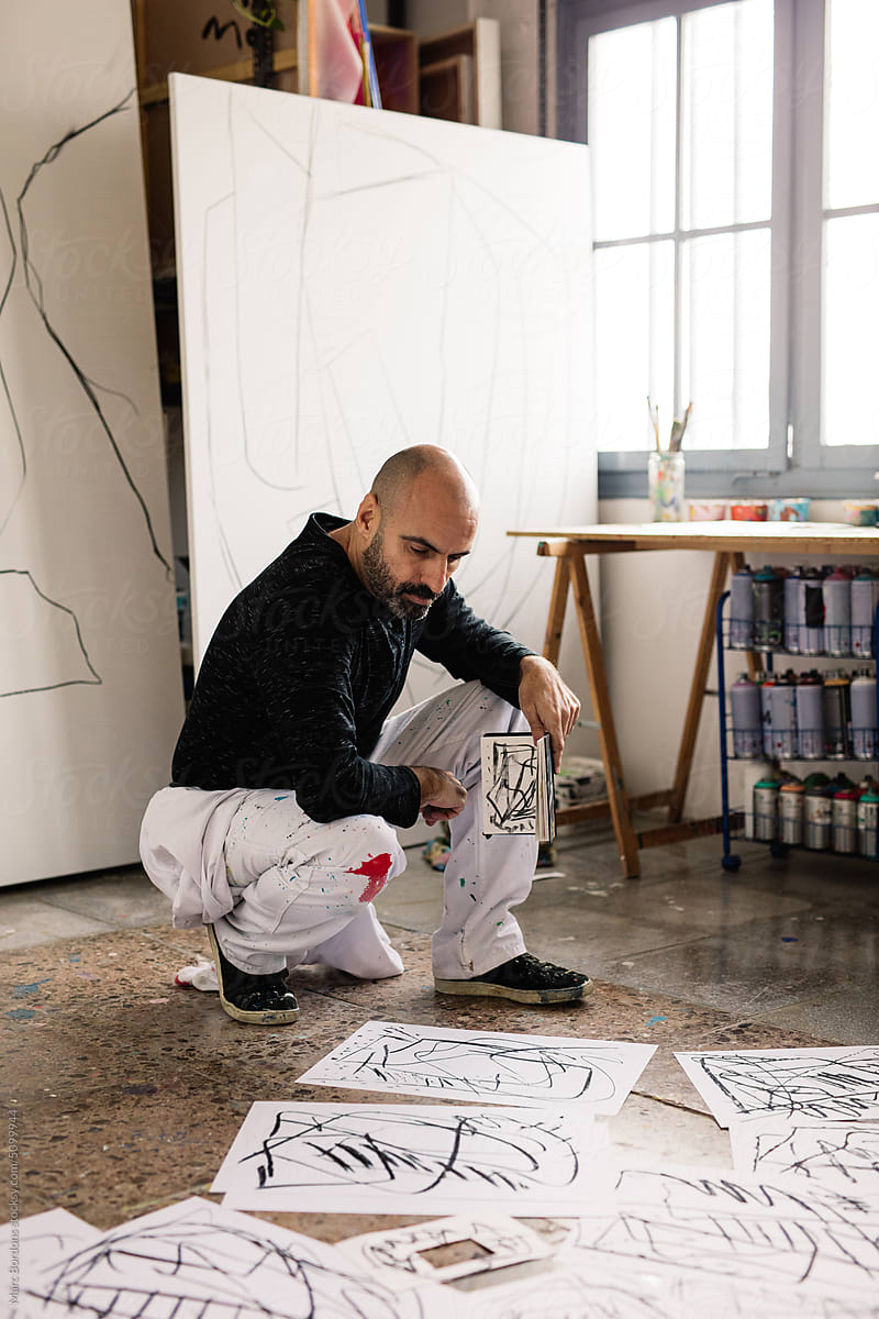 an artist reviews his sketches on the floor