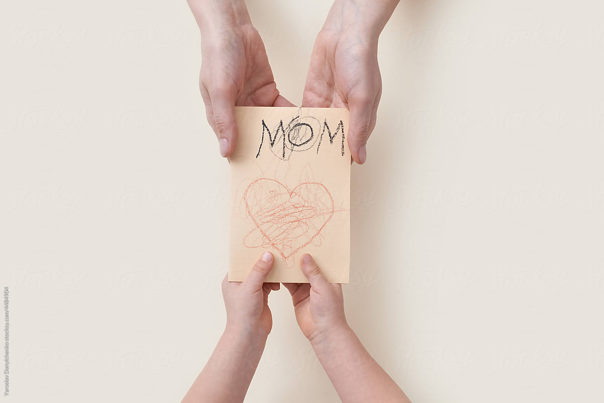 Child giving paper greeting card to mom