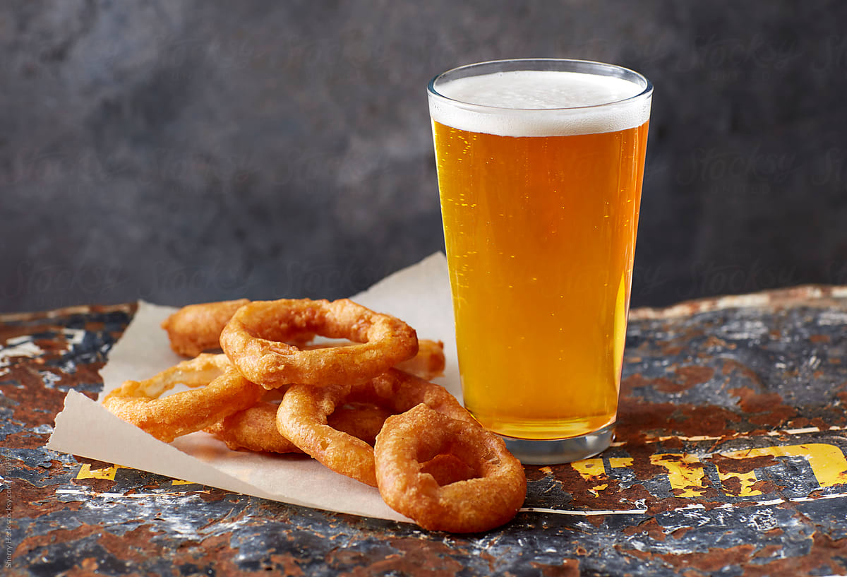 Light beer with onion rings on distressed metal surface
