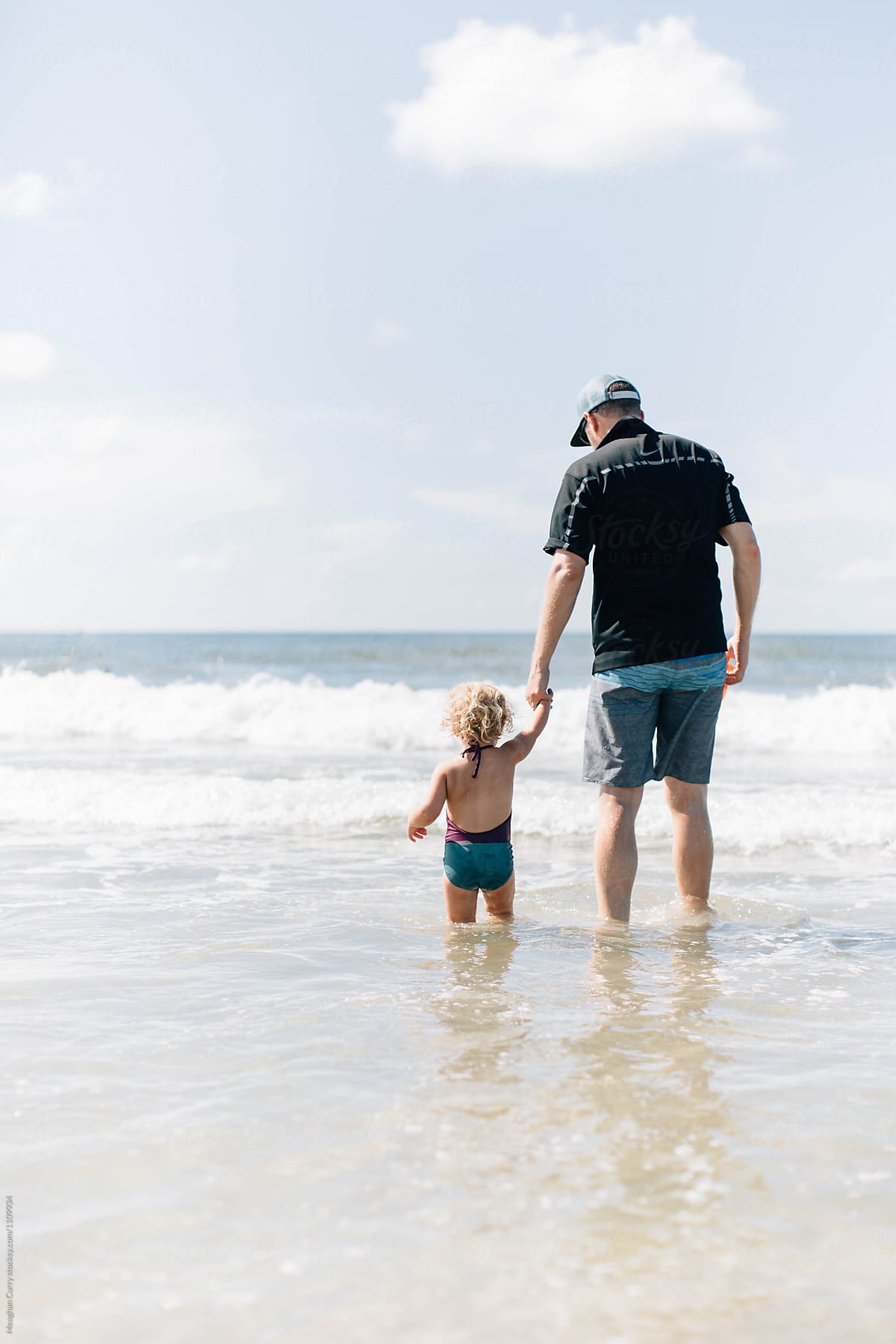father and child play in the waves at the ocean