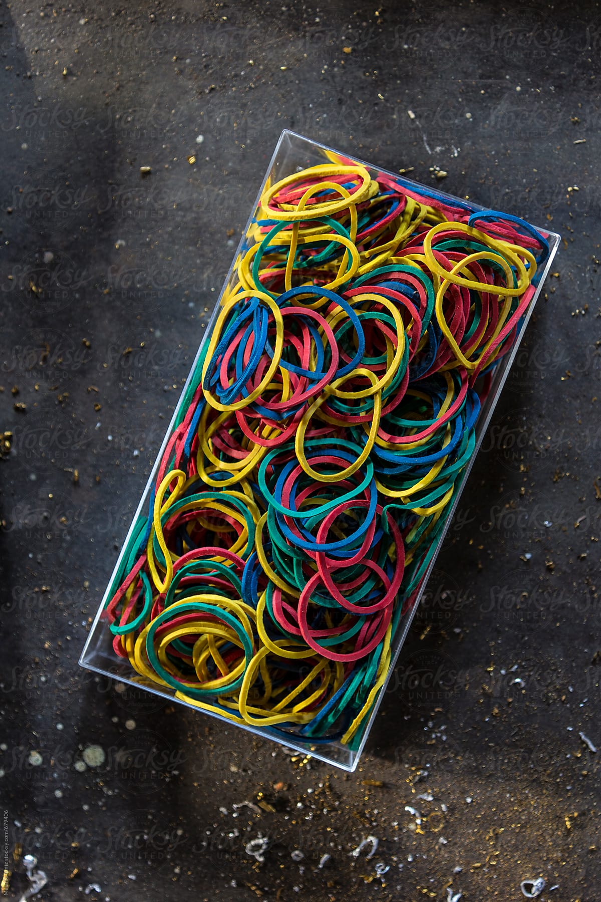 Colorful rubber bands in a box on dark metal background