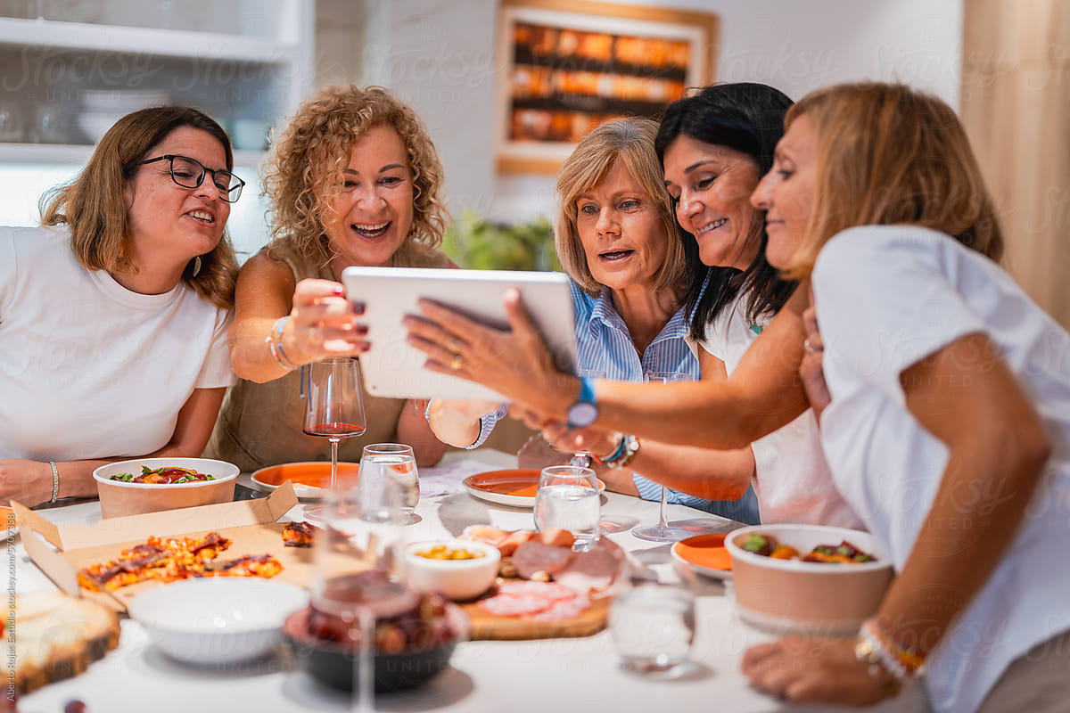 Company of cheerful friends taking selfie at table