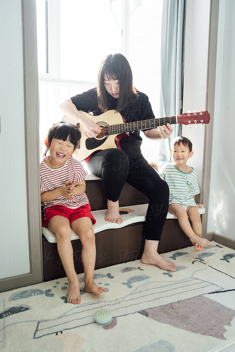 Mother with her kids playing guitar at home