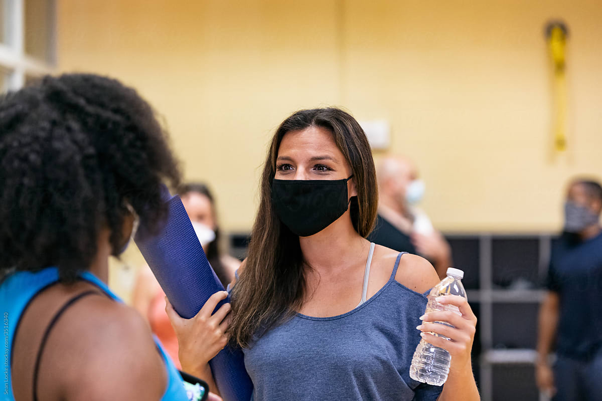 Gym: Woman Talks With Instructor Before Stretching Class