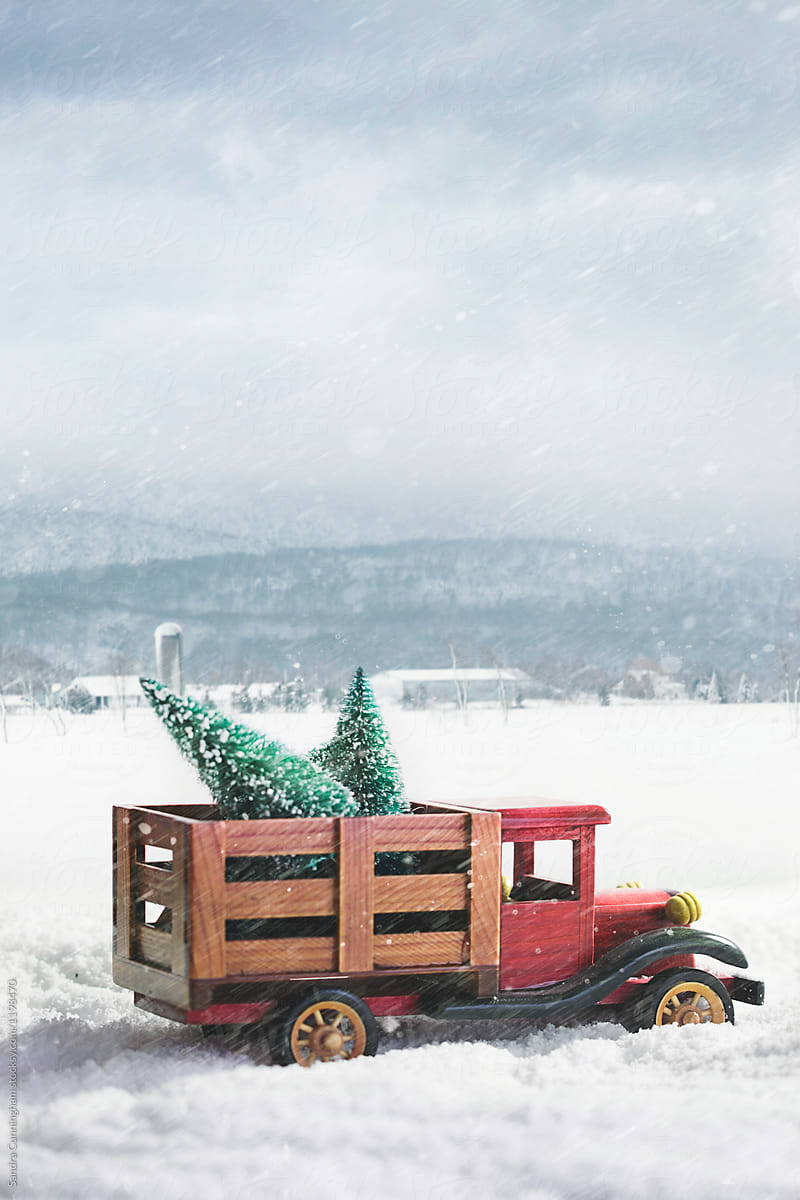 Small toy truck with christmas trees in snow storm