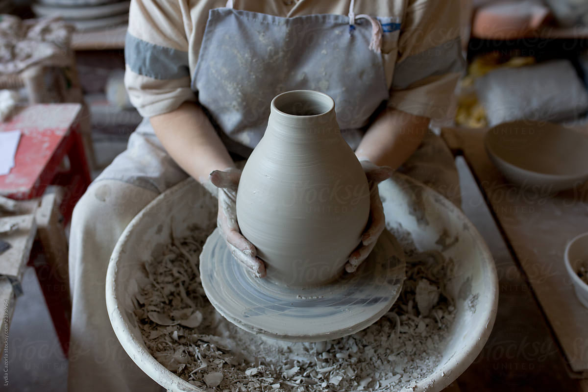 Woman making pottery on spinning wheel in her workshop