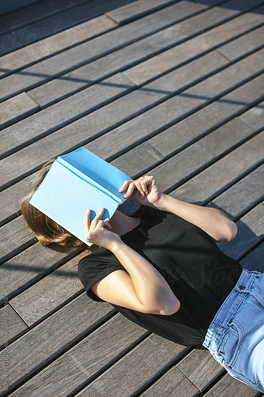 Young Beautiful Woman Hiding Her Face With A Book Lying On A Wooden 4902