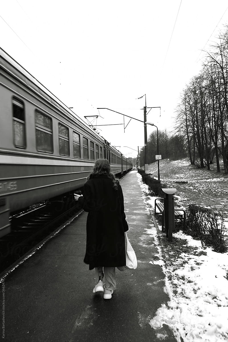 black and white photo of a girl walking along the train on the platform during a solo romantic trip