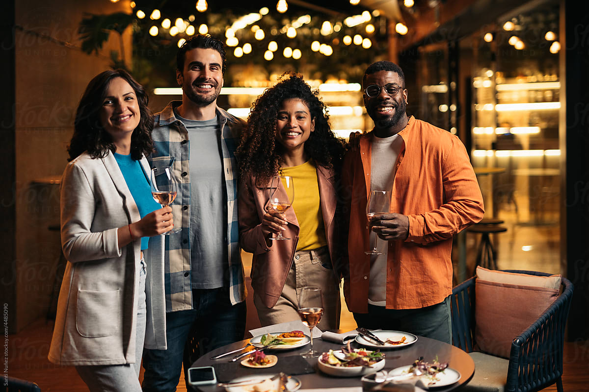 Cheerful diverse friends enjoying wine in cafe