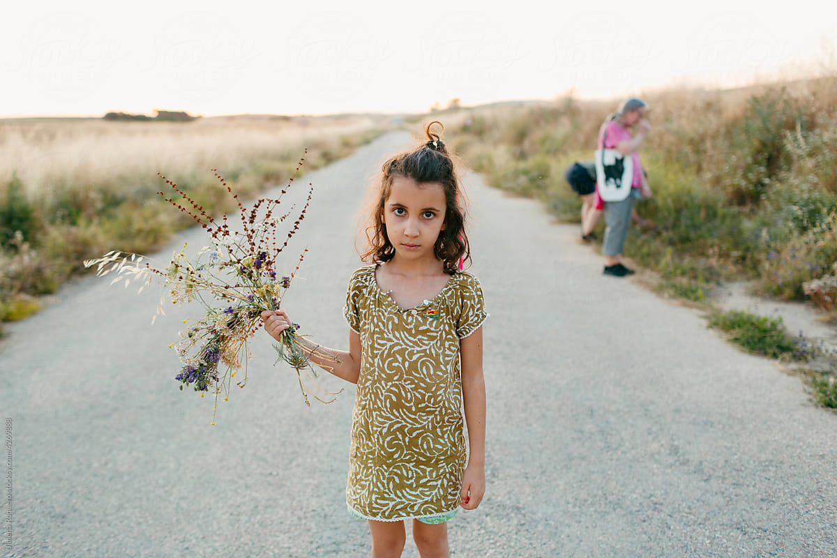 Kid posing outdoor with a bunch of wild flowers
