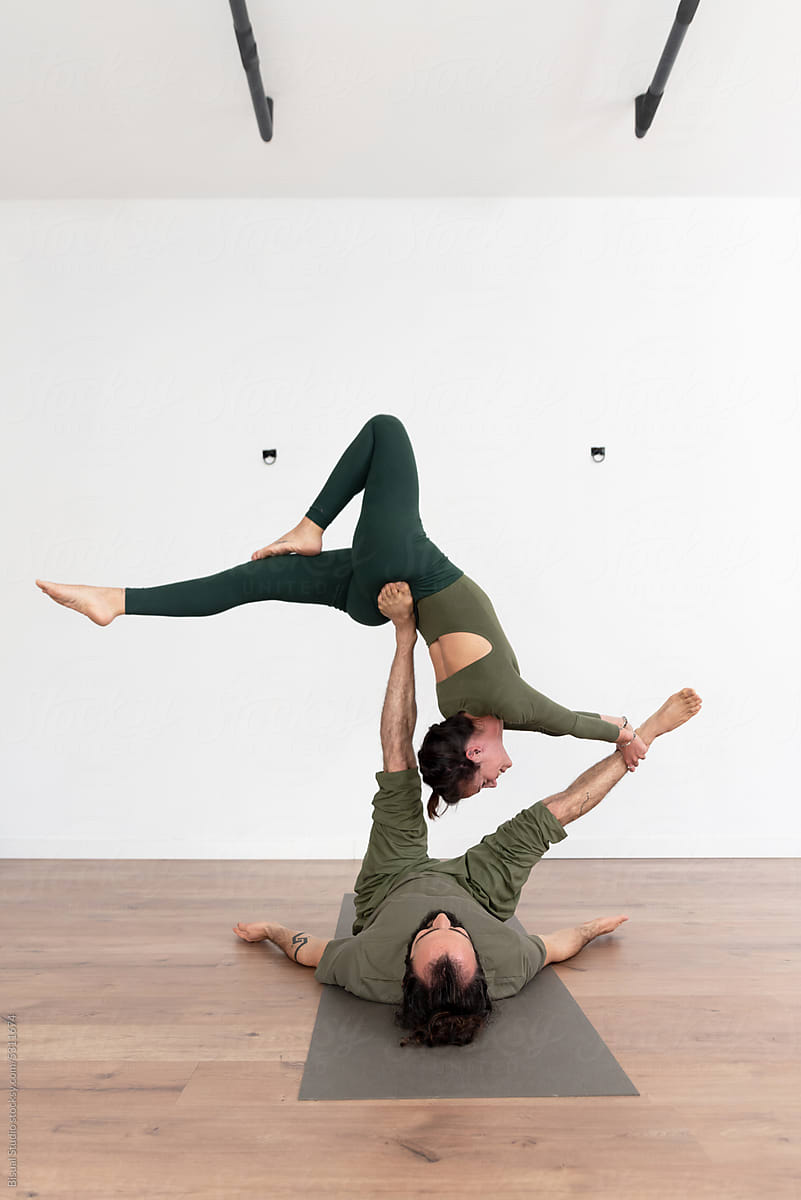 Flexible woman and man performing acro yoga pose
