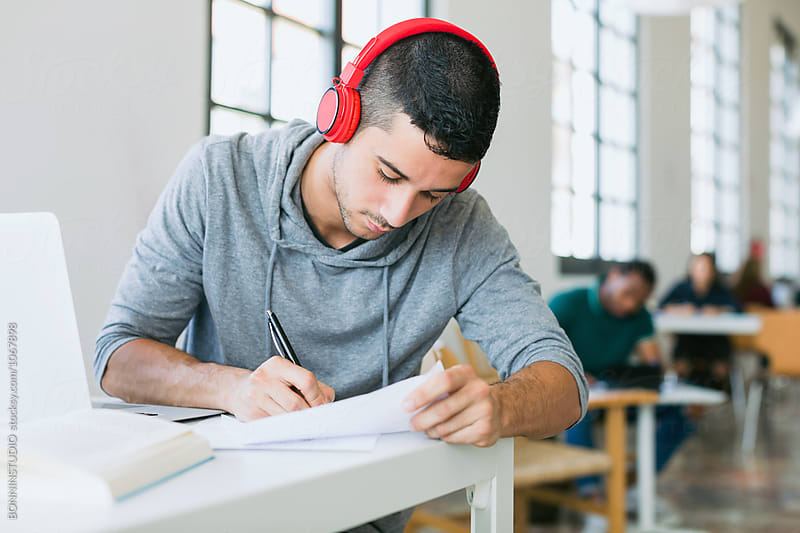 University student wearing red headphone working in a library.